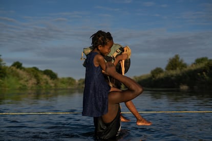 Un hombre lleva a su hija a hombros para cruzar el Río Bravo entre Del Río y Ciudad Acuña.