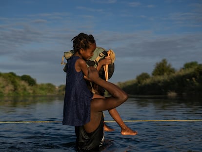 Un hombre haitiano con su hija a hombros cruza el Río Bravo entre Del Río (Texas) y Ciudad Acuña (México), este 22 de septiembre de 2021.