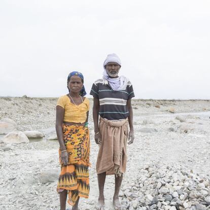 Shoma (derecha) y Sugi Munda,de 56 y 45 años respectivamente, posan para una fotografía mientras aplastan guijarros y piedras a lo largo del cauce del río Diana en Red Bank Tea Estate, en la región de Dooars. La plantación de té, que cerró en 2013, comenzó funcionar mal en 1993, indica Shoma. La compañía primero dejó de arreglar las casas de los trabajadores. Unos meses más tarde, cerró. A continuación, una serie de propietarios diferentes se hizo cargo y cada uno de ellos reabrió el negocio durante unos meses al año antes de desaparecer de nuevo. A los trabajadores no se les han pagado los salarios atrasados.