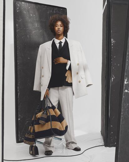 Traje de lana gris de Isabel Marant, chaqueta de lana con camisa de seda a rayas y corbata, todo de Dior, guantes de cachemir de Blundell, mocasines de piel de Mango, reloj de acero con esfera beis de Rolex, bolso de peluche a rayas, con minibolsos y cantimplora, de MaxMara.