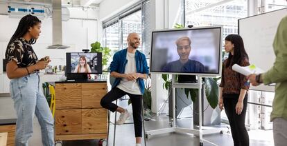 Varios empleados celebran una reunión en formato híbrido. 