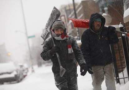 Dois homem carregam pás para limpar a neve em Detroit.