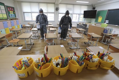 Dos empleados desinfectan un aula de un colegio de Gwangju (Corea del Sur) antes de la vuelta de los alumnos a las clases presenciales.