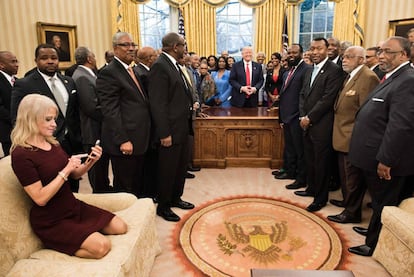 La consejera del presidente Kellyanne Conway revisa su teléfono tras tomar una foto a Donald Trump y un grupo de líderes de universidades afroamericanas.