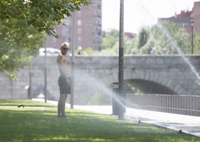 Un hombre se refresca en los aspersores de Madrid Río, este sábado. Las noches también serán calurosas, con mínimas de hasta 24 grados en Almería o 23 en lMelilla.