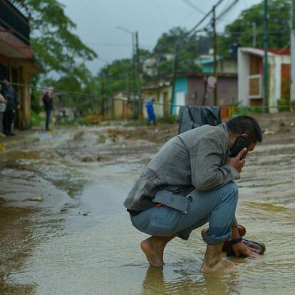 Un hombre limpia sus zapatos en la corriente provocada por las inundaciones en Xalapa, Veracruz, el 1 de julio 2024. 