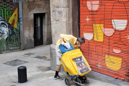 Un cartero deja correo en un local cerradode Barcelona, el 30 d ejunio de 2020.