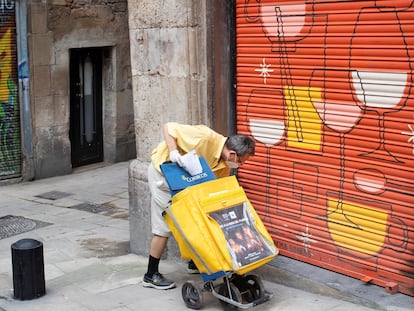 Un cartero deja correo en un local cerradode Barcelona, el 30 d ejunio de 2020.