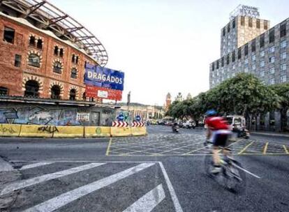 Un cicilista pedalea ante las obras paradas del centro comercial de Las Arenas, con la calle Tarragona en primer término.