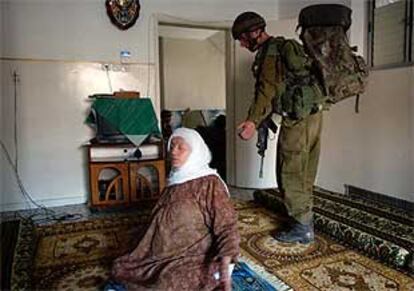Una palestina se sienta en el suelo, mientras un soldado israelí registra su casa, en Tulkarem.