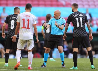 El árbitro turco, Cuneyt Cakir, da instrucciones a los jugadores de ambas selecciones tras una jugada del partido.