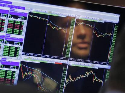 La imagen de un operador se refleja sobre la pantalla de cotizaciones, en la Bolsa de Nueva York. 