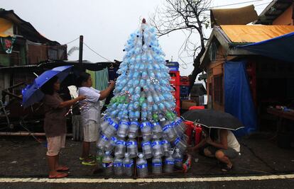 Víctimas de súper tifón Haiyan decoran su árbol de Navidad improvisado con latas y botellas vacías en la ciudad devastada de Anibong, ciudad de Tacloban, Filipinas central, un mes después que el tifón azotase el centro de Filipinas.