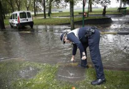 Un policía municipal observa las balsas de agua que se formaron en el centro de la capital navarra donde se registró una fuerte tormenta. EFE/Archivo