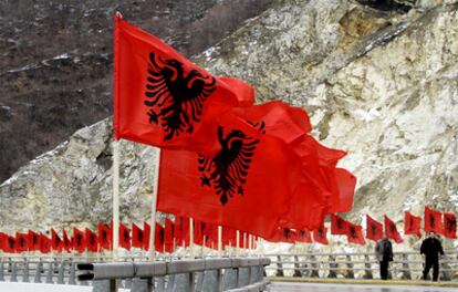 Hombres de etnia albanesa caminan por una carretera plagada por banderas nacionales de Albania en el segundo aniversario de la independencia de Kosovo.