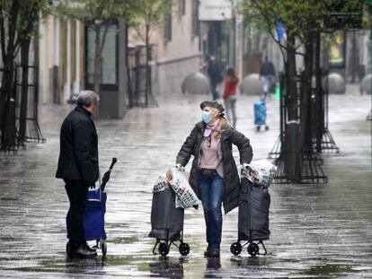 Una mujer protegida con mascarilla y guantes sanitarios realiza compras durante el sexto día del estado de alarma por coronavirus, en Madrid.
 
 