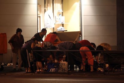 A photo taken in June 2012 shows a group of people rummaging through dumpsters placed at the exit of a shopping mall in Madrid.