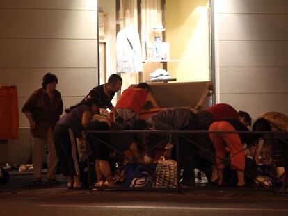 A photo taken in June 2012 shows a group of people rummaging through dumpsters placed at the exit of a shopping mall in Madrid.