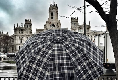 Una persona se protege bajo un paraguas de la lluvia en Madrid.