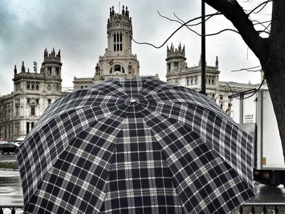 Una persona se protege bajo un paraguas de la lluvia en Madrid.