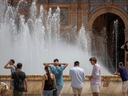 Varios jóvenes se refrescan en la fuente de la plaza de España en Sevilla, este martes.