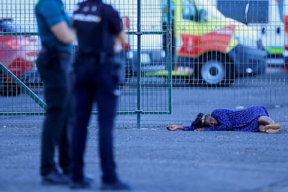 Una mujer espera en el suelo a los equipos de Cruz Roja, después de desembarcar del cayuco en el puerto de Arguineguín, el domingo 20 de octubre. 