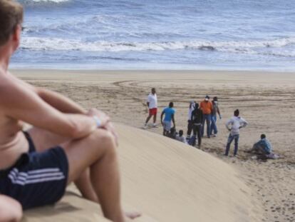 Dos turistas observan al grupo de inmigrantes aislados el mi&eacute;rcoles en la playa de Maspalomas.