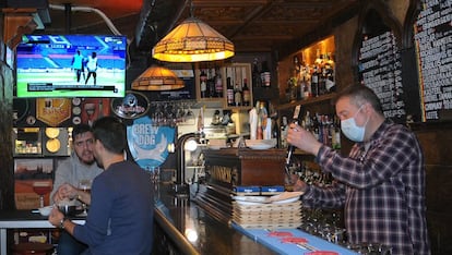 Víctor Rey sirve unas cervezas en su bar, El rincón del Greco. De fondo, un informativo de LaLiga Santander. 