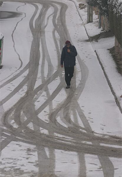 Un vecino de  Manzanares el Real camina por una calle completamente nevada.