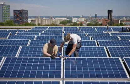 Dos operarios instalando un panel solar en el techo de la universidad de Dresde, Alemania. 