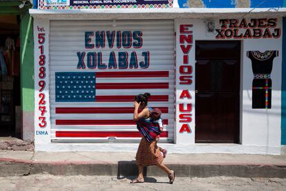 Una mujer pasa con su hijo frente a un local de envíos hacia y desde EE UU en Joyabaj (Guatemala).