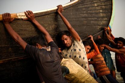 Unos refugiados rohingya empujan un barco pesquero desde el mar en la playa de Shamlapur en Cox's Bazar (Bangladesh)