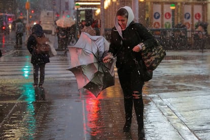 Una mujer camina bajo la lluvia en el distrito de Times Square en la ciudad de New York City.