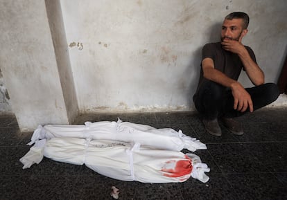 Un hombre junto a los cadáveres de dos niños este domingo en ciudad de Gaza.