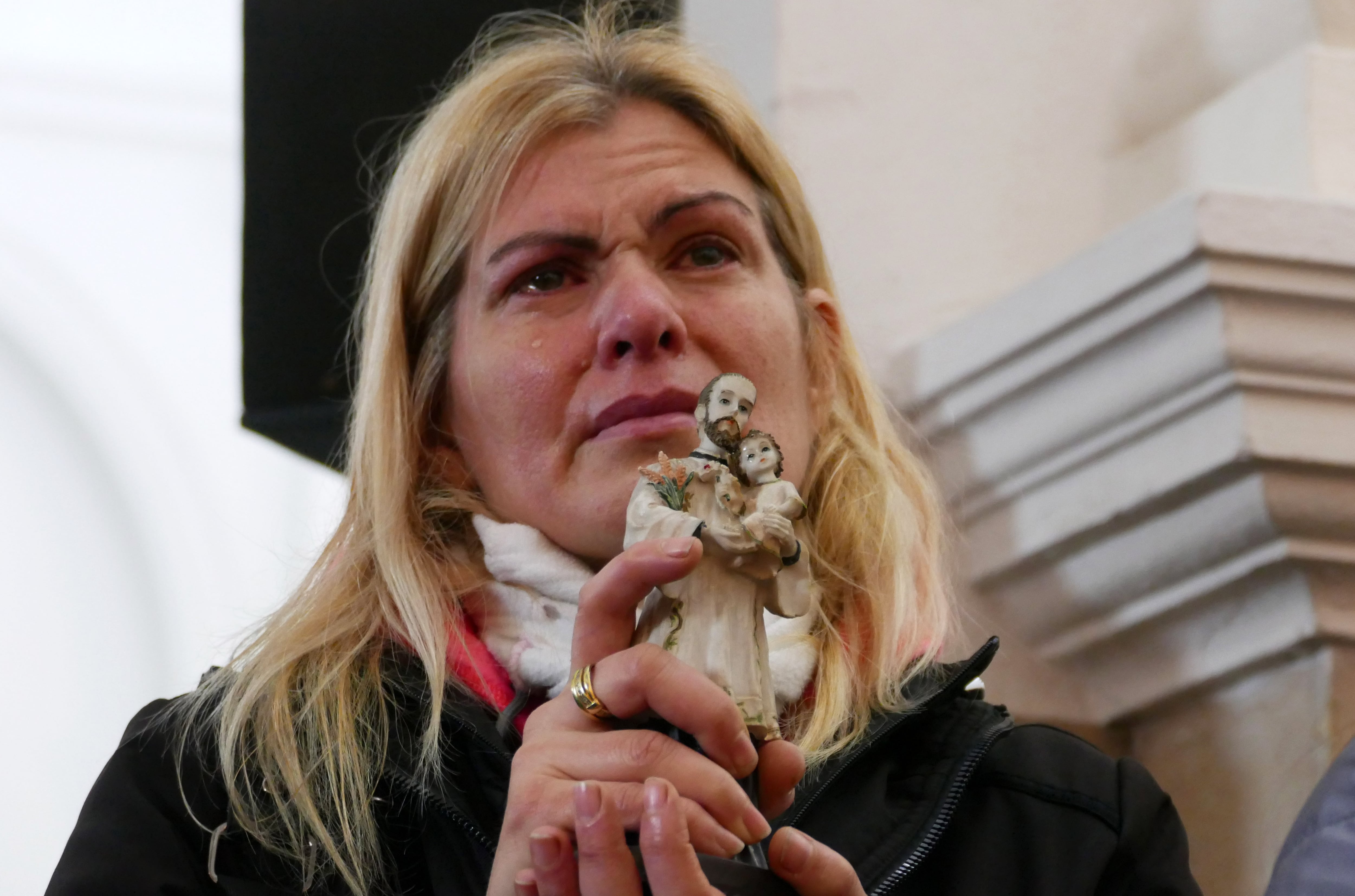 Una mujer sostiene una figura de San Cayetano.
