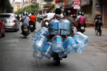Un hombre transporta con una moto bidones de agua este lunes en Hanoi (Vietnam).