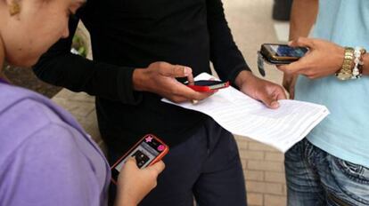 Tres jóvenes usan sus teléfonos móviles.