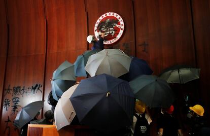 Un manifestante pinta el escudo de Honk Kong que preside el Parlamento durante las protestas en la ciudad, el 1 de julio de 2019. Precisamente el día en que se cumplían 22 años del traspaso de la antigua colonia británica a la soberanía china, Decenas de manifestantes entraron por la fuerza en el Parlamento, mientras en las calles del centro de la ciudad centenares de miles de personas participaban en una marcha de protesta contra el Gobierno autónomo. La jefa de Gobierno de Hong Kong condenó la “extrema violencia” de los que penetraron en el Parlamento.