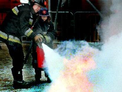 Un bombero enseña a un niño a apagar un incendio durante el simulacro de ayer.