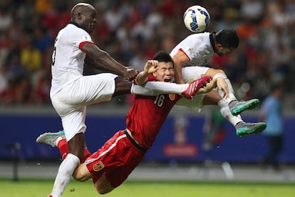 El jugador chino Sun Ke (c) flanqueado por dos jugadores del equipo de Hong Kong durante un partido de clasificación de la Copa del Mundo en Shenzhen (China).