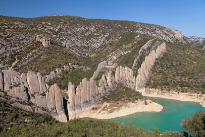 La gran muralla de Finestras (Huesca). Se parece a la Gran Muralla, por eso se la conoce popularmente como “la Muralla China de Finestres”. La razón es que esta muralla ondulante de roca caliza, semejante a la doble fila de placas dorsales de un estegosaurio, se yergue asombrosa en la parte oscense del macizo del Montsec y a solo un kilómetro y medio de la leridana. Para llegar a Finestras —o Finestres, en catalán—, lo más sencillo es acercarse desde Estopiñán hasta el puente de Penavera conduciendo por una pista de tierra y luego caminar siete kilómetros (una hora y media) por la prolongación de la misma. Una vez en Finestras, un pueblo fantasma a orillas del Noguera Ribagorzana —río que anegó sus mejores tierras y lo dejó sin vida al construirse en 1960 el embalse de Canelles—, se sube en 15 o 20 minutos a la ermita de San Marcos, que es el mejor mirador de este prodigio natural, y luego en media hora a la románica de San Vicente, cuyas ruinas yacen sobre otras de un castillo medieval que hay entre las paredes de 20 metros de altura de la muralla. Cuatro horas y media de paseo, yendo y volviendo de un lado para otro, no nos las quita nadie. Tampoco es mala idea hospedarse en el albergue de Montfalcó, en la localidad de Viacamp, y hacer desde allí el camino a pie hasta Finestras en unas cuatro horas, para después regresar en un vehículo 4x4 del propio alojamiento. Al día siguiente, se pueden recorrer las famosas pasarelas de Montfalcó, un camino de tablas vertiginoso que zigzaguea arriba y abajo por los acantilados de hasta 500 metros de altura que bordean el embalse de Canelles.
