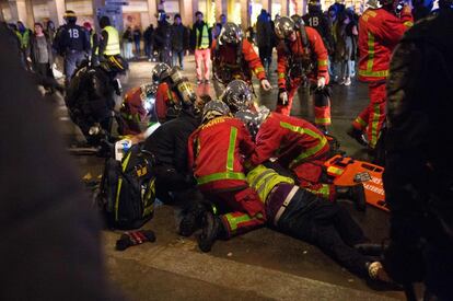 Los bomberos atienden a dos personas durante los disturbios de este sábado en París personas, donde se han contabilizado más de un centenar de heridos.