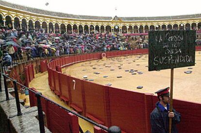 Un arenero muestra un cartel anunciando la suspensin de la corrida de la Feria de Abril, en la Real Maestranza de Sevilla.