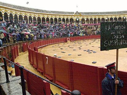 Un arenero muestra un cartel anunciando la suspensión de la corrida de la Feria de Abril, en la Real Maestranza de Sevilla.