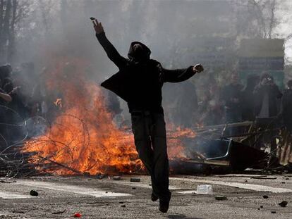Un manifestante arroja una piedra contra la policía