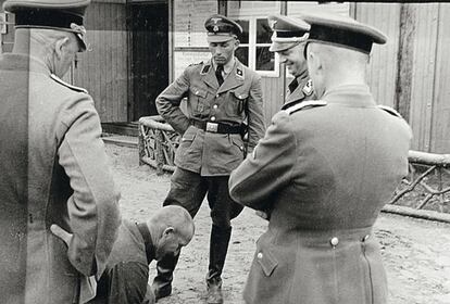 El comandante Koch y algunos de sus hombres de las SS, de pie ante un prisionero postrado en el suelo de Sachsenhausen en 1937.