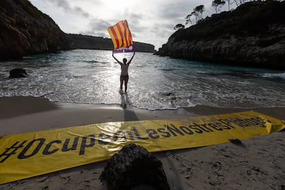 Una mujer sostiene la bandera de Mallorca en la protesta pacífica en Cala del Moro, este domingo.