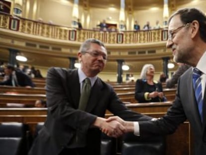 El presidente del Gobierno, Mariano Rajoy, estrecha la mano del ministro de Justicia, Alberto Ruiz Gallardón, en el Congreso de los Diputados.