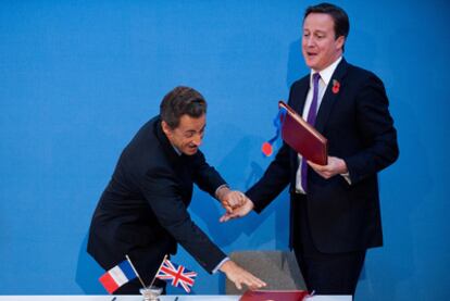 El presidente francés, Nicolas Sarkozy (izquierda), y el primer ministro británico, David Cameron, bromean tras firmar el tratado, ayer en Londres.