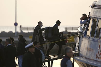 Un oficial de Frontex acompaña a un migrante cuando se sube al barco en el que será devuelto a Turquía desde la isla griega de Lesbos.